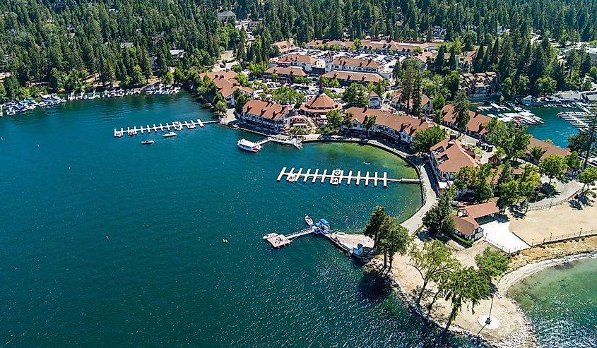 Aerial shot of a gorgeous summer landscape at Lake Arrowhead with rippling blue water, boats sailing, boat docks and mountains covered in lush green trees in Lake Arrowhead California