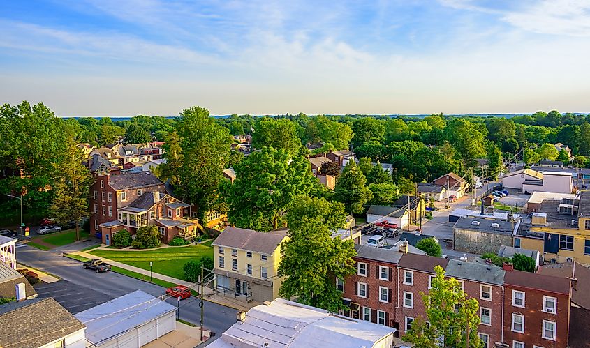 Aerial perspective of West Chester, Pennsylvania, showcasing suburban houses against a backdrop of a vibrant sunset sky.