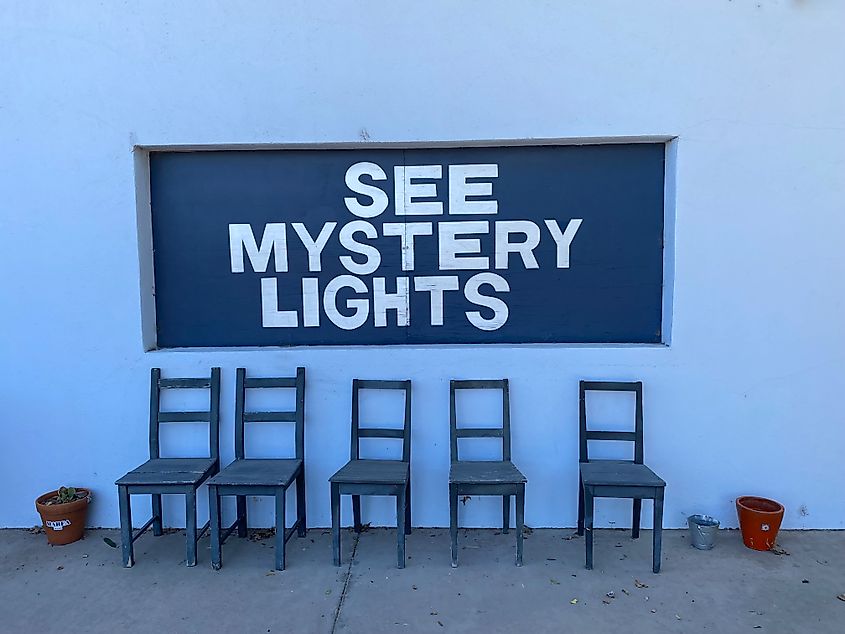 A painted wall mural with the words “See Mystery Lights” behind 5 wooden chairs. 