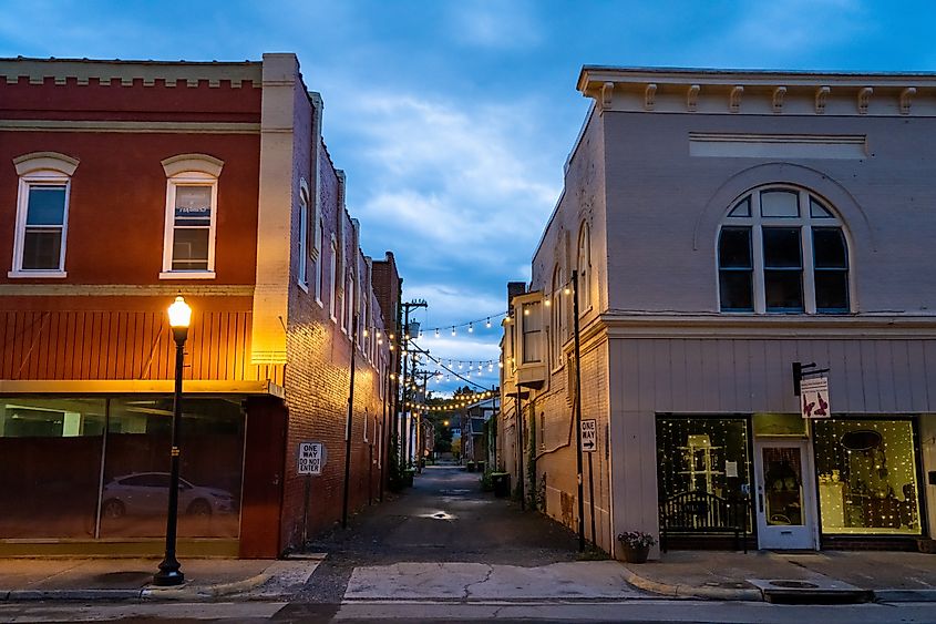 Alleyway in Pulaski, Virginia, with string lights between brick buildings at dusk.