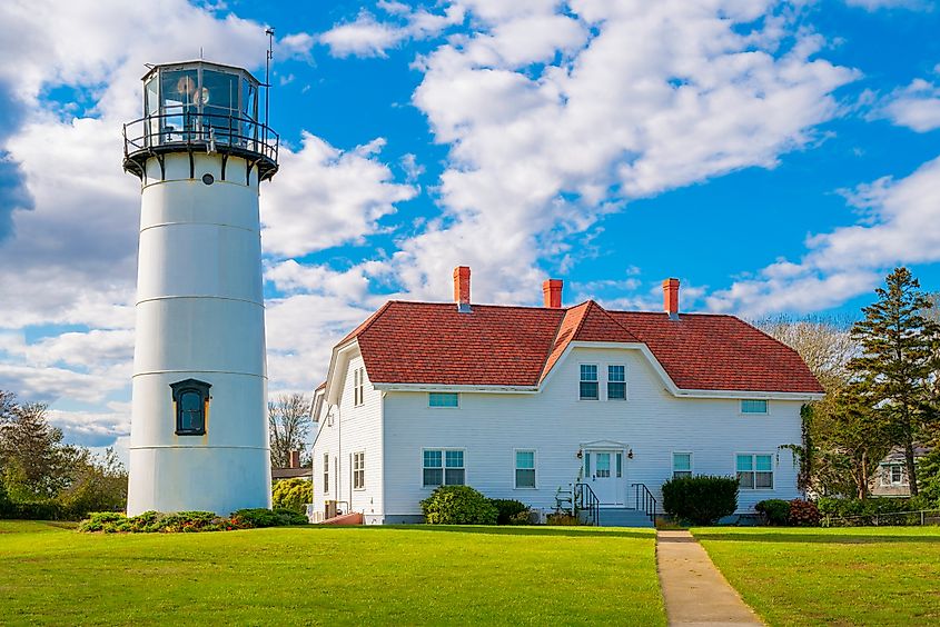 Chatham Light and the red-roofed keeper's house under dramatic clouds in the blue sky