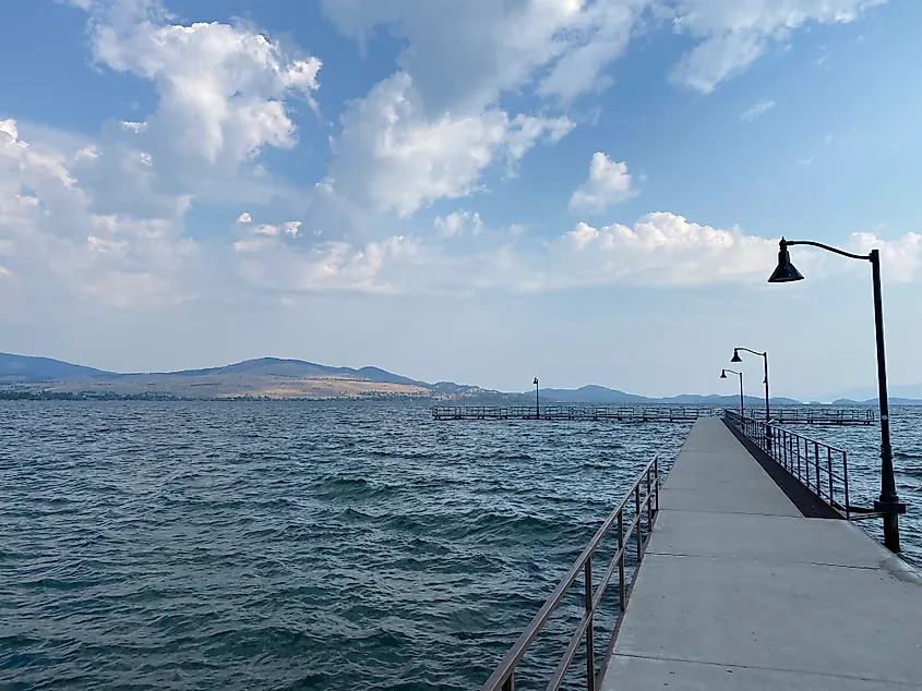 A long public dock leads out into a massive alpine lake.