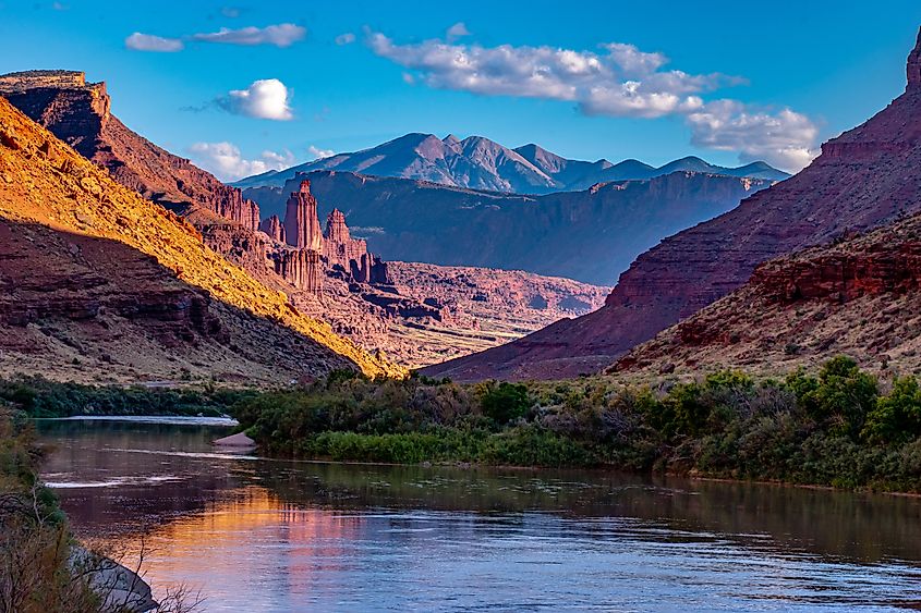 The Fisher Towers glow in the golden hour light while the Colorado River below rests in the shadows.