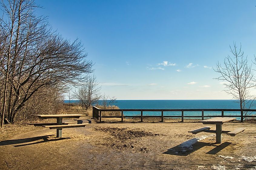 picnic tables face a peaceful Lake Michigan from atop a bluff at Lion's Den Gorge, near Grafton