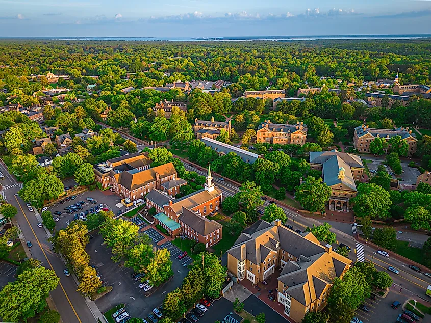 Aerial view of downtown Williamsburg, Virginia, at dusk, with historic buildings and tree-lined streets softly illuminated in the fading light.