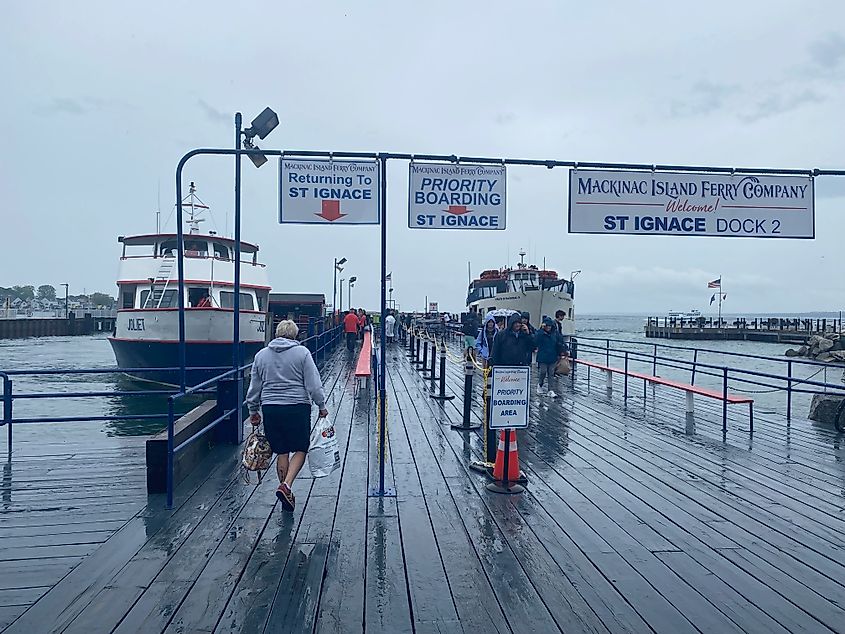 A man boards a ferry to St. Ignace, while a fresh batch of tourists arrives at Mackinac Island