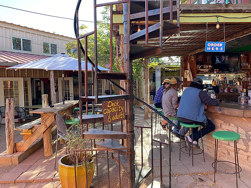 Three men sit at the bar of a quirky, outdoor beer garden. 