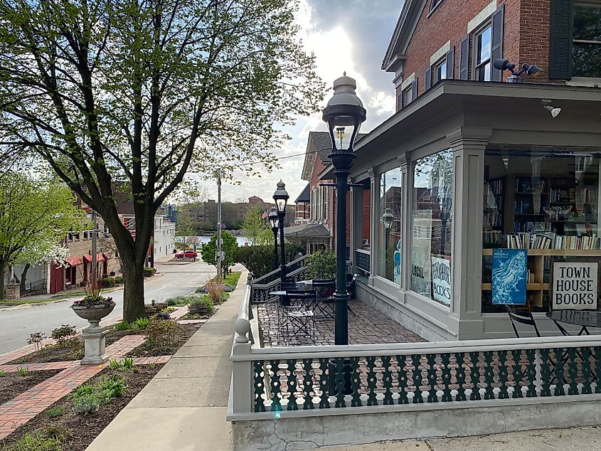 A quaint corner bookstore looks down to a municipal river. 