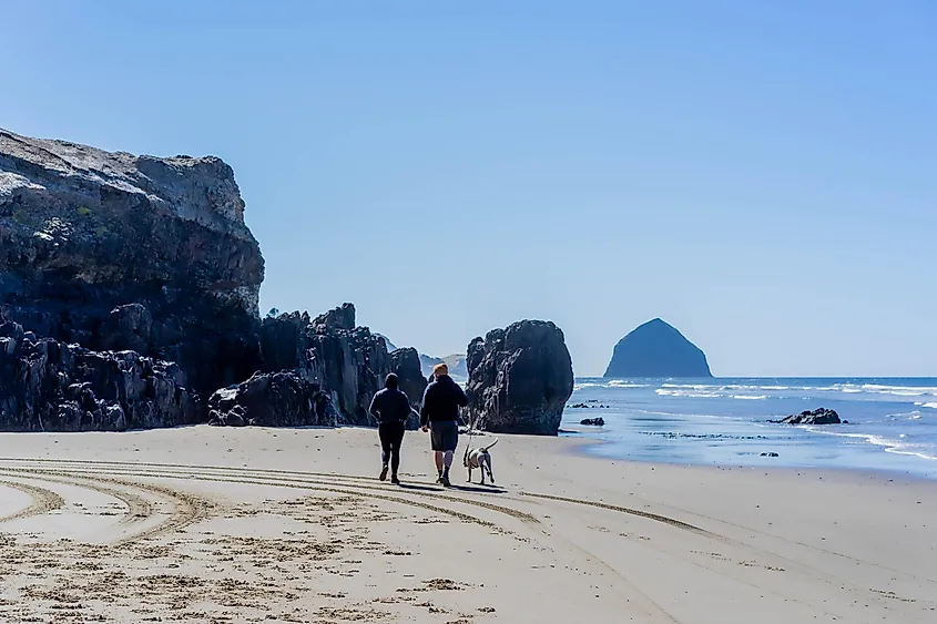 A couple walks their dog on McPhillips Beach, Pacific City, Oregon