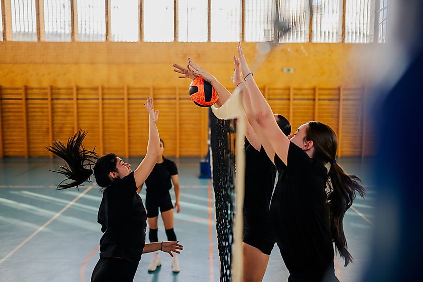 Side view of a two female volleyball teams in action.