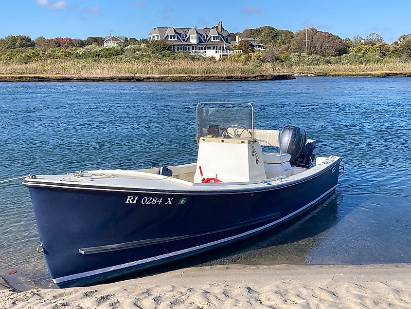 Anchored motorboat in Narrow River across from a beach house in Narragansett, Rhode Island
