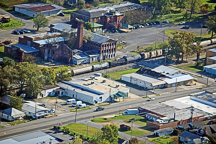 Aerial view of Fort Payne, Alabama, showcasing a mix of industrial, commercial, and residential buildings, with train carriages on the tracks and roads crisscrossing the landscape.