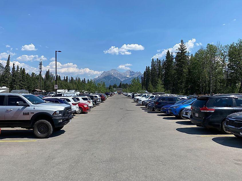 A large public parking lot in between the mountains of Banff National Park