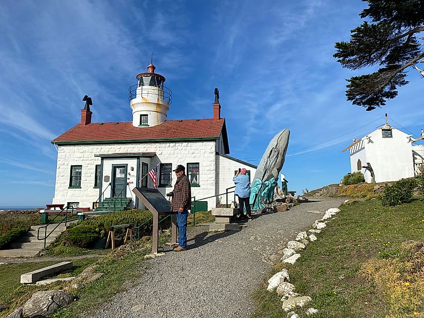 An older couple takes pictures and reads the interpretive signs of a historic light station. 