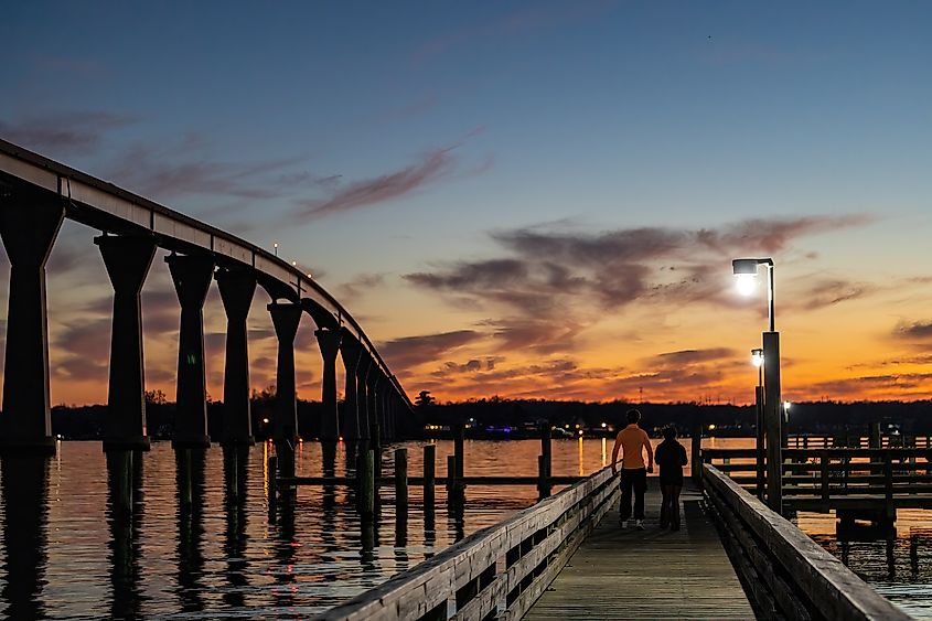 A young couple on a pier below the the Solomons Bridge at night, or Gov. Thomas Johnson Bridge. Editorial credit: Alexanderstock23 / Shutterstock.com