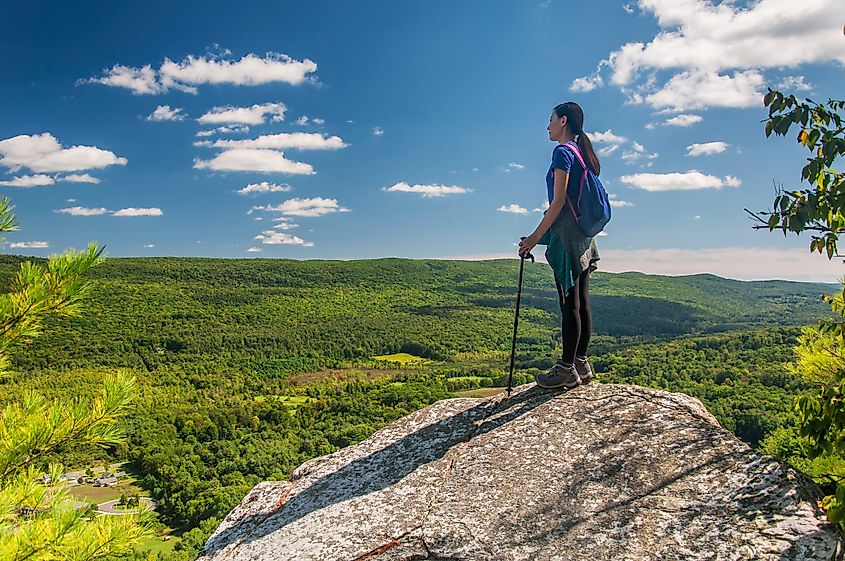 An Asian woman standing atop a large rock on Monument Mountain in Great Barrington, Massachusetts.