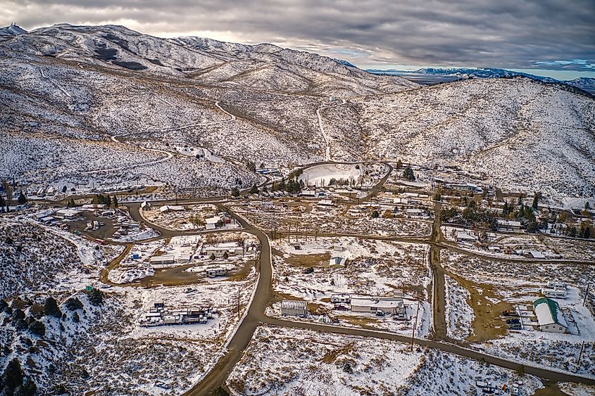 Aerial view of the small town of Austin, Nevada, along Highway 50, showing a cluster of buildings nestled in a rugged mountainous landscape