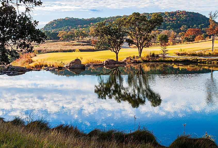 Brilliant fall colors reflect in the calm waters of a lake at Boot Ranch in Fredericksburg, Texas.