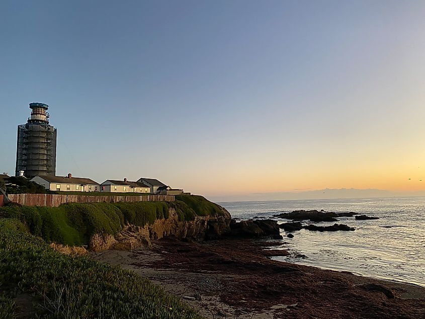 California's tall, slim, and historic Pigeon Point Lighthouse (under construction), watching as the sun sets on a beautiful October day.