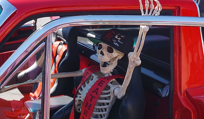 Skeleton driver in sporty red pickup truck promises a scary ride at fall apple festival car show.