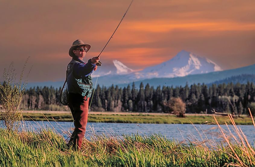 A man fishes near Sisters, Oregon, with the town's namesake mountains in the background.