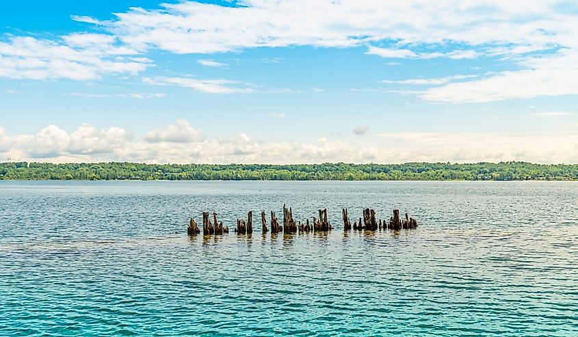 Landscape of the Huron Lake water and old withered wooden dock posts or marina wreck at sunny day in Georgian Bay near Spirit Rock Conservation Area at Wiarton, Ontario, Canada