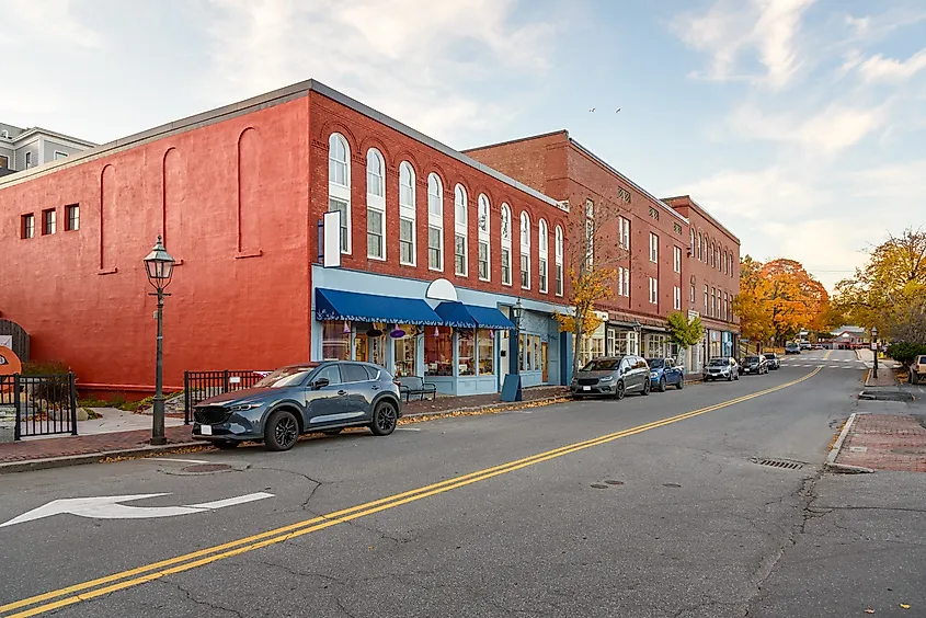 Traditional American brick buildings with colourful shops along the street in a historic downtown district at dusk in autumn in Bath, Maine.