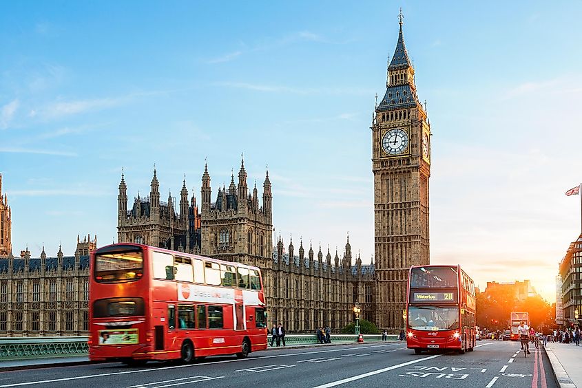 Buses zoom past Big Ben and the Palace of Westminster.