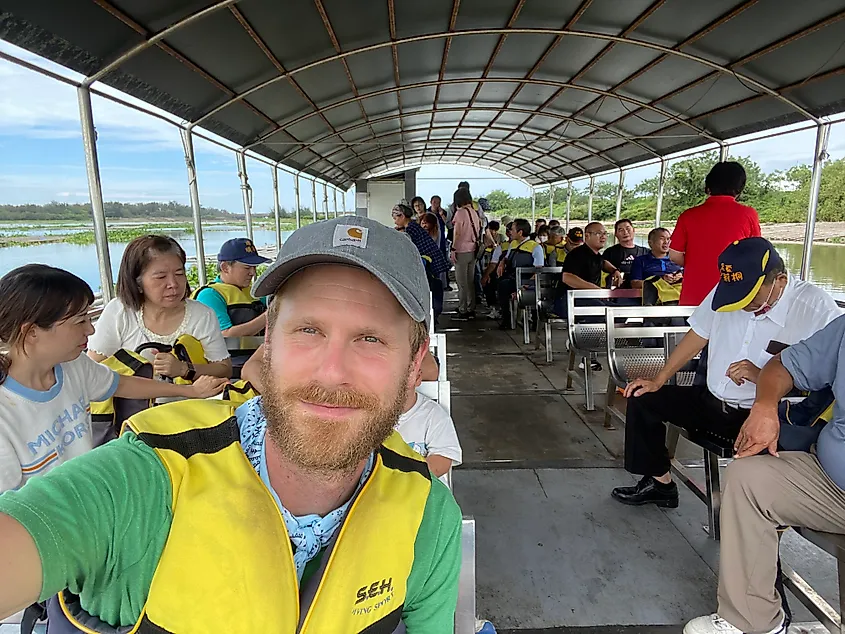 A man takes a selfie aboard a packed wetland tour boat.