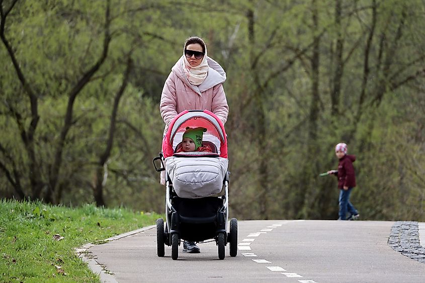 Woman walking with a baby pram in a spring park in Moscow, Russia. Image Credit Oleg Elkov via Shutterstock.