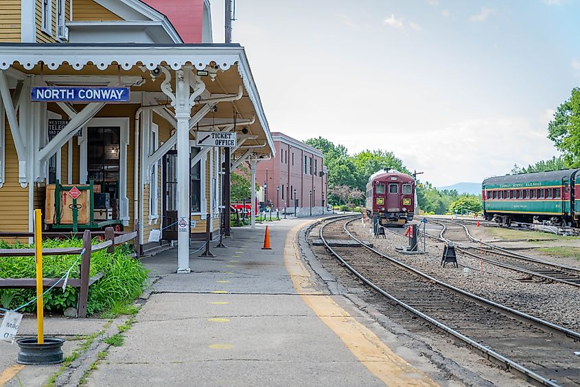 Scenic railcar at a historic rail depot in North Conway, NH, with an empty platform.