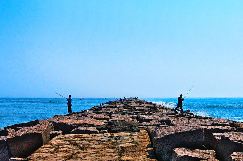 Fishermen fishing on jetty on clear sunny day on Gulf of Mexico.