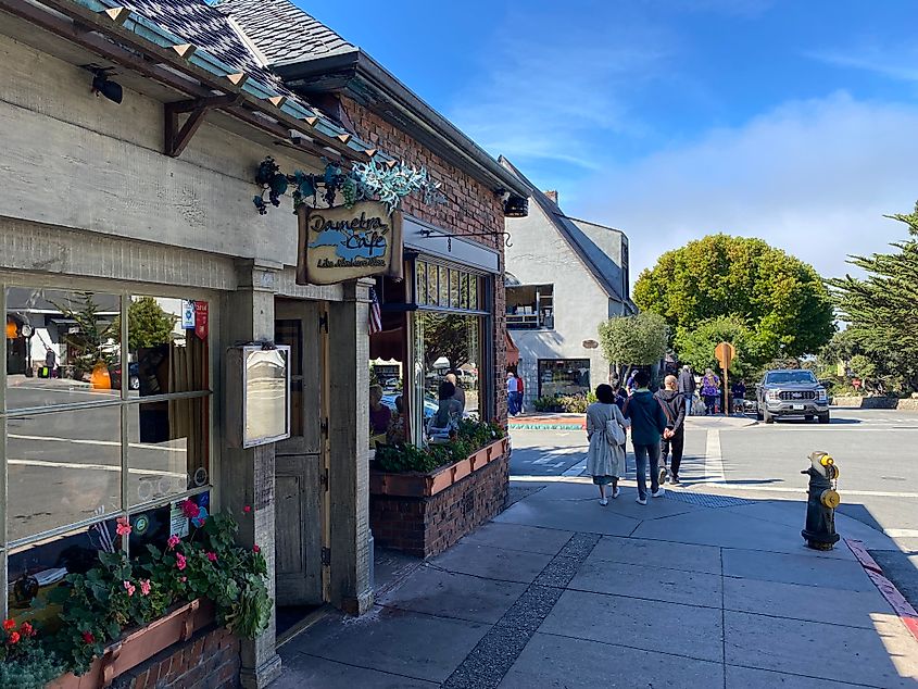 People strolling along a clean, quaint, and sunny street in Carmel-by-the-Sea, California. 