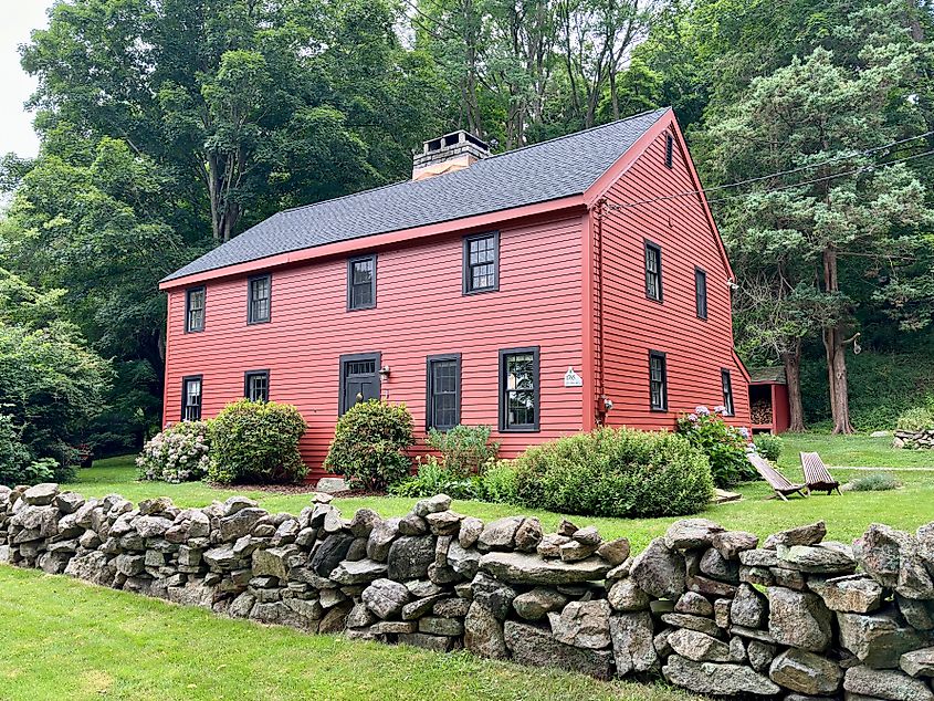 Vintage, red house with stone wall in foreground in Guilford, Connecticut.