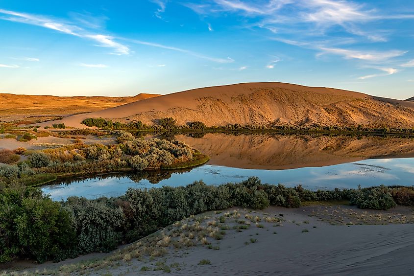 Desert oasis of water with vegetation along with blue sky and clouds at Bruneau Dunes, Idaho..