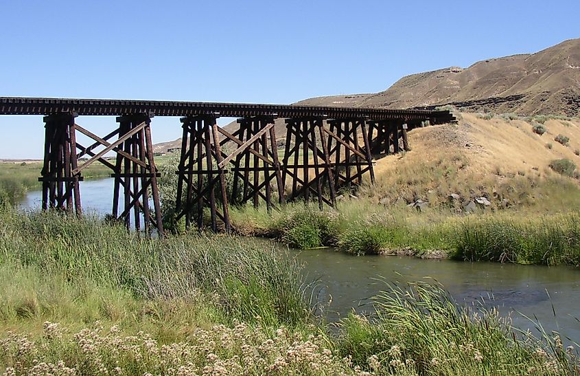 Lower Crab Creek, eight miles above its confluence with the Columbia River, looking east. The Saddle Mountains rise to the right, with a winding creek surrounded by arid terrain and scattered vegetation.