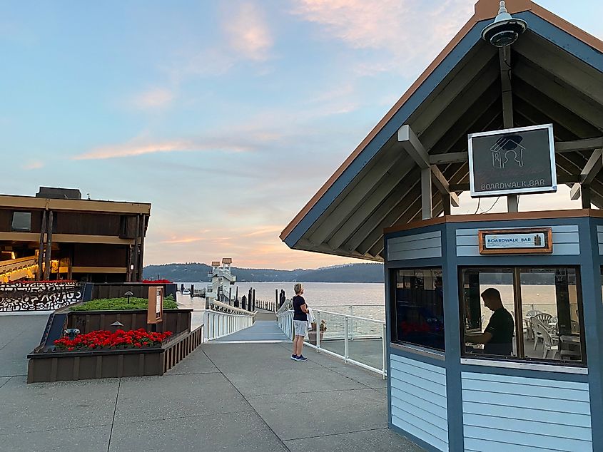 Sunset at a small bar hut that stands before a lakeside walkway.