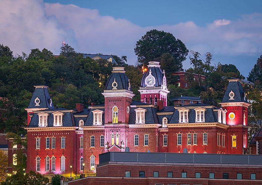 The illuminated facade of Woodburn Hall against the backdrop of trees on the downtown campus of West Virginia University in Morgantown.