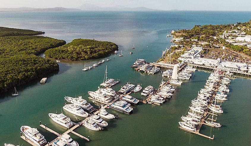 Marina town with waterfront river view of yachts and boats in sea water. Carins Port Douglas aerial view.