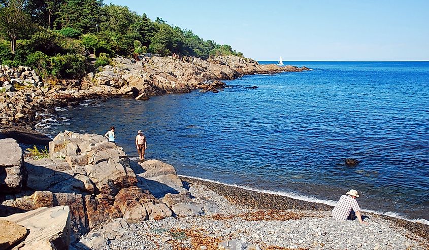 Several folks enjoy relaxing on the rocky shores near Ogunquit, Maine