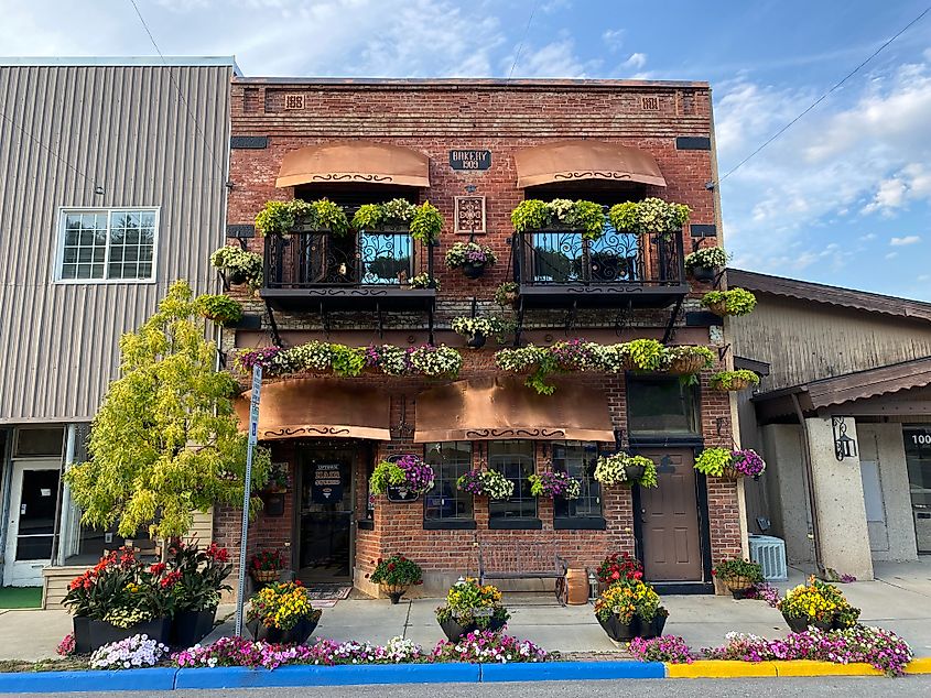 A two-storey red brick building covered in green plants and flowers.