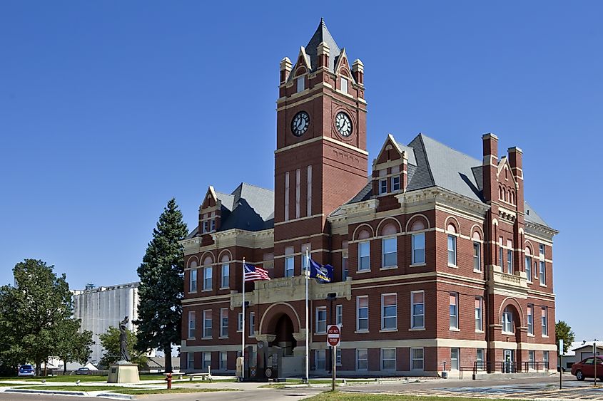 The Romanesque-style Thomas County Courthouse in Colby, Kansas, standing near large grain elevators.