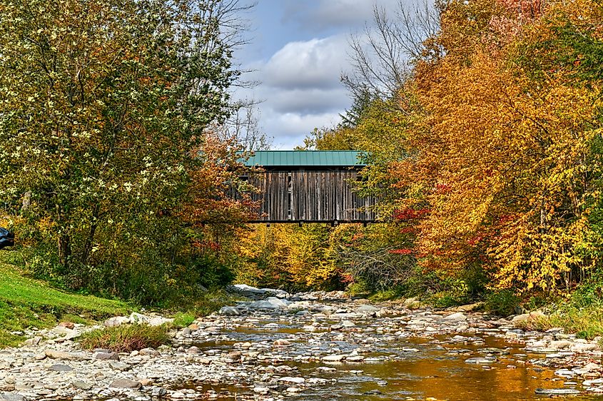 Grist Mill Covered Bridge surrounded by fall foliage in Cambridge, Vermont