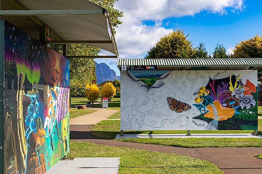 Sheffield, Tasmania, known for its iconic outdoor art exhibition, featuring vibrant murals displayed throughout the town. The scene reflects a strong connection to travel, fine arts, and outdoor tourism culture, creating a lively holiday ambiance.