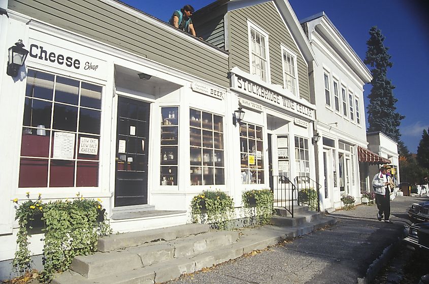 White wooden storefronts in Stockbridge, Massachusetts, surrounded by vibrant autumn foliage.