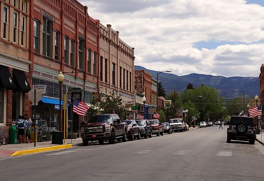  A bustling street scene in Salida, Colorado, featuring historic red brick buildings lined with various shops and decorated with American flags.