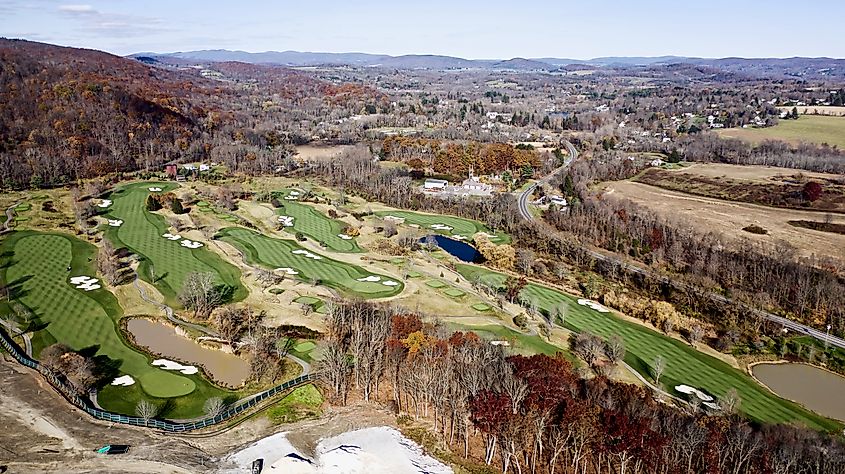 Aerial drone shot taken over a beautiful golf course on a sunny day with perfect patterns on the grass, clean sand & autumn foliage all around, upstate in Amenia, New York.