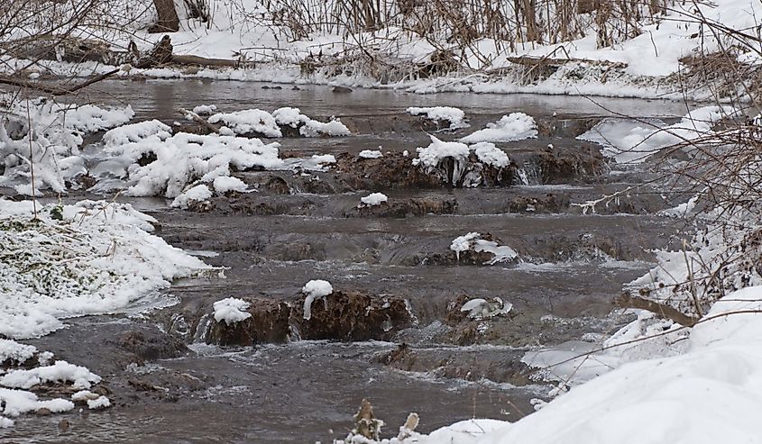 Snow lines the banks of the creek at Dunning's Spring Park in Decorah, Iowa, USA.