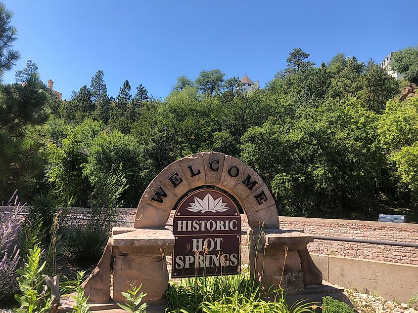 Welcome to Hot Springs, South Dakota sign surrounded by natural scenery.