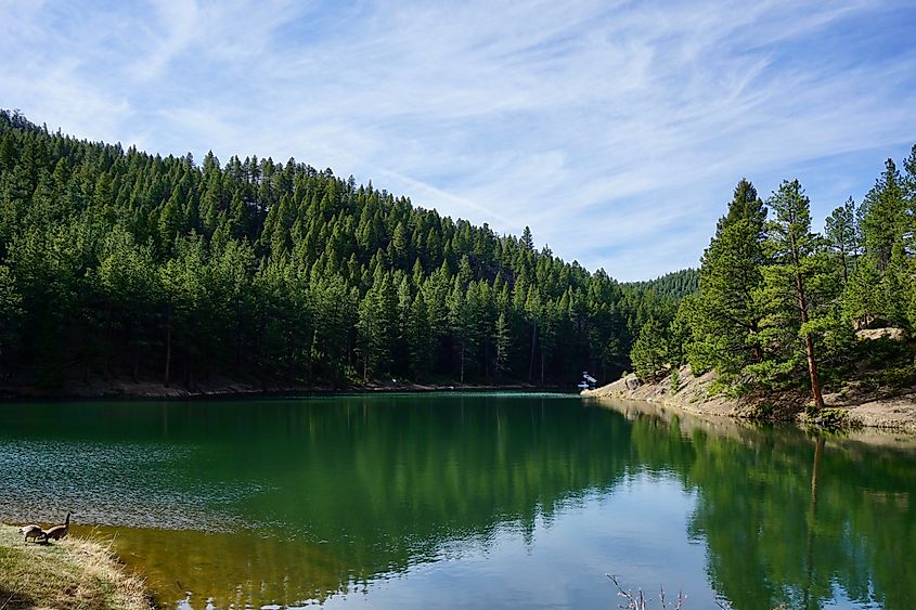 Palmer Lake Reservoir in Colorado, surrounded by pine-covered hills and rugged mountain scenery.